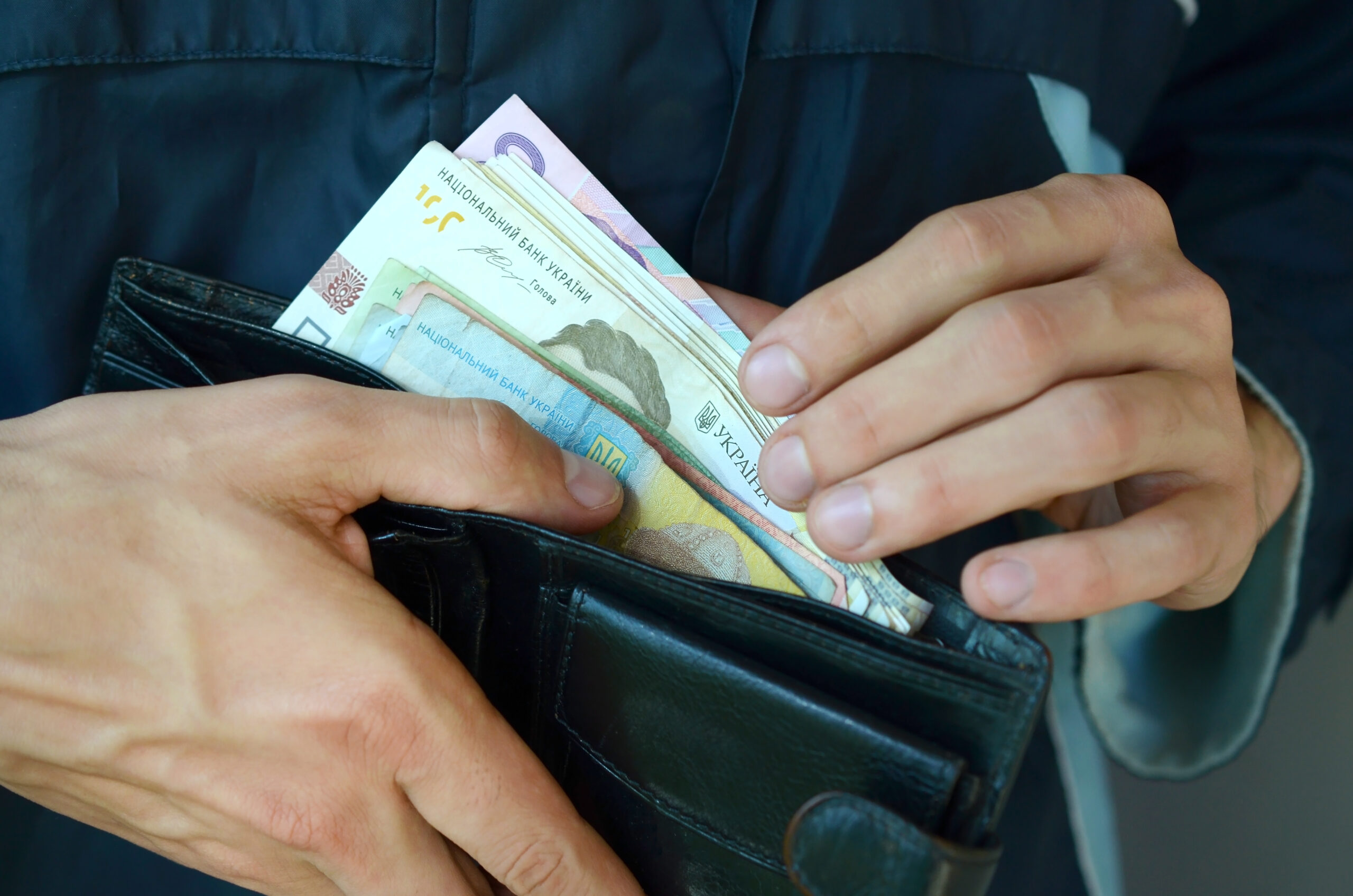 Close up male hands opened the wallet or purse with ukrainian money currency hryvnia. Salary in Ukraine. Big amount of money